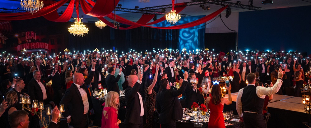 Ballroom full of attendees holding up cellphone lights.